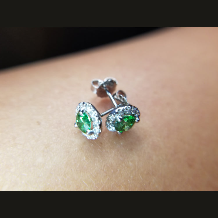 14k white gold earrings featuring stunning green diamonds. The diamonds have a total weight of 0.83ct. A halo of  24 diamonds surround the center stones.