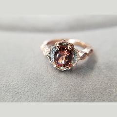 A beautifully made rose gold and zircon ring. This custom piece features a 2.13ct oval zircon, surrounded by 12 diamonds. This ring is a size 7.