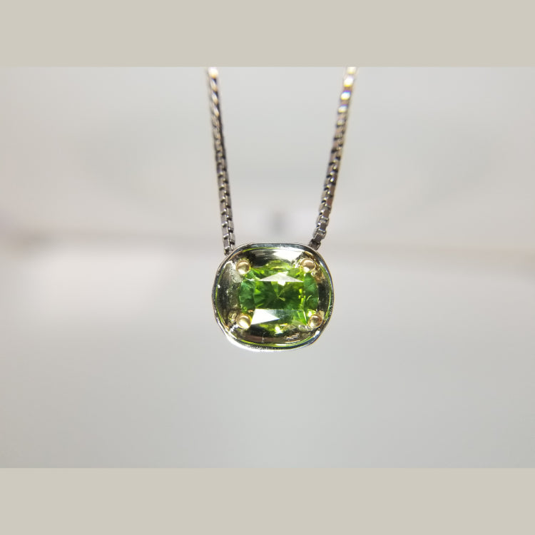 This custom 14k white gold and 18k yellow gold pendant that features a 1.32ct oval peridot is the perfect piece  to dress up any outfit. It hangs beautifully on am 18" white gold box chain. 