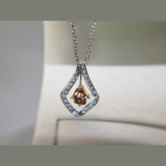 A stunning custom pendant! This pendant features a 1.10 cognac kite diamond, in a rose gold dangling head. Surrounding the floating cognac diamond are 0.13ct of diamonds. 